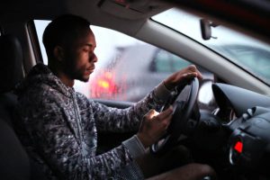 African man using his phone while driving.