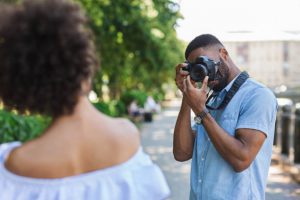 African-american photographer taking photos of beautiful woman in summer park