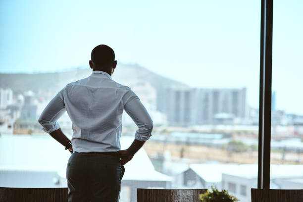 Rearview shot of a businessman looking out the window in an office