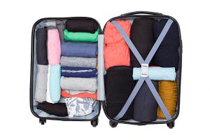 Open suitcase with clothing on white background