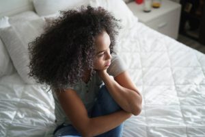 Young lady overthinking, looking sad and worried on the bed