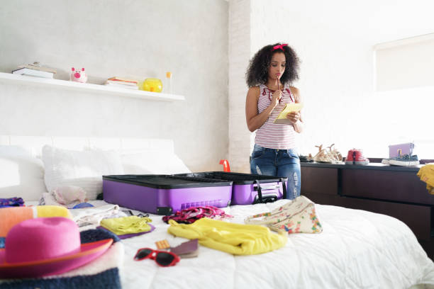 Girl preparing suitcase for vacation, looking at checklist to get ready for a trip