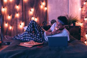 Young man eating pizza and watching a movie