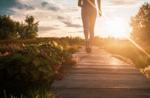 Close up of unknown woman running in park at sunset.