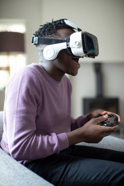 Excited Teenage Boy Playing Video Game At Home Wearing Virtual Reality Headset