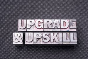 upgrade and upskill phrase made from metallic letterpress blocks on black perforated surface