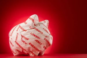 Piggy bank wrapped with emergency paper in front of a red background