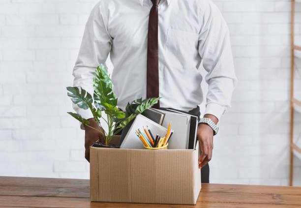 Quitting job concept. Unrecognizable African American employee with box of his belongings at office.