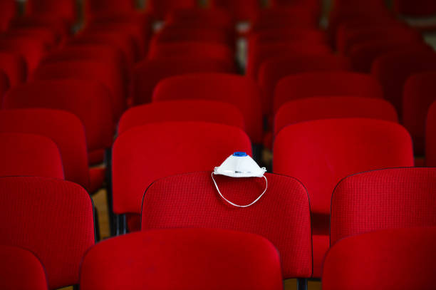 An empty cinema hall with a face mask one of the headrest of one of the seats. Coronavirus & Social Distancing concept.