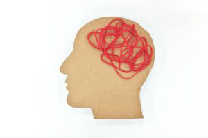 Human male head profile silhouette  with tangled red yarn as brain gear. 