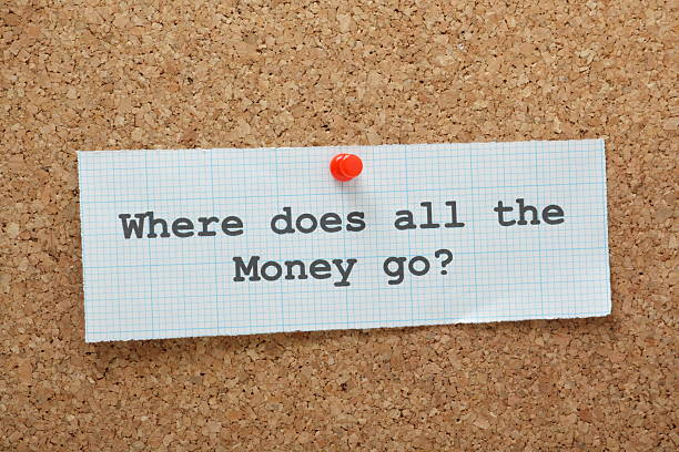 The phrase Where Does All the Money Go? typed on a piece of graph paper and pinned to a cork notice board.