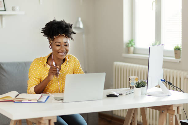 Happy African American Businesswoman Wearing Headphones, Looking at Laptop Screen, Having An Online Meeting With Partners Clients