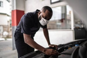 Auto mechanic man with face mask working at auto repair shop