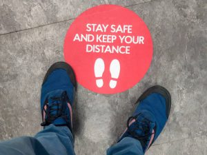 A sign on the floor of a shop, advising customers regarding social distancing guidelines.