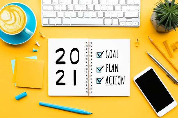 2021 new year concept with goal, plan, action text on notepad with office accessories.