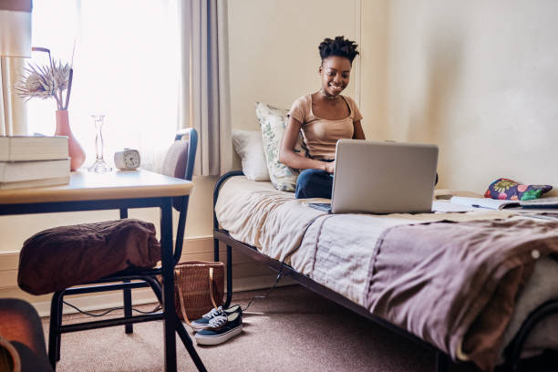 Shot of a young female university student using a laptop while studying in her room