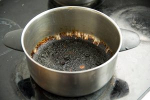 Empty burnt pot with black bottom over the stoves