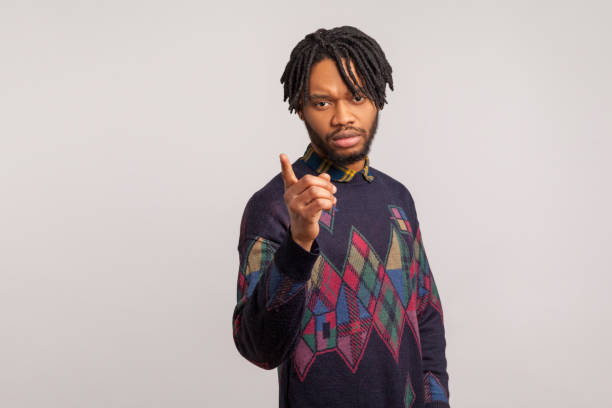 Strict serious African man with dreadlocks in casual sweatshirt pointing finger looking at camera, scolding .