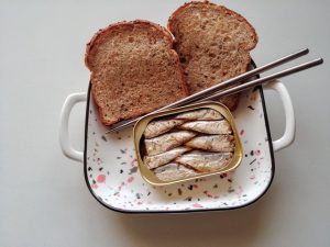 A plate of bread, chopsticks and sardines in a can