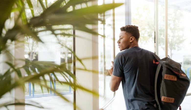 A young man with a backpack, about to exit a building