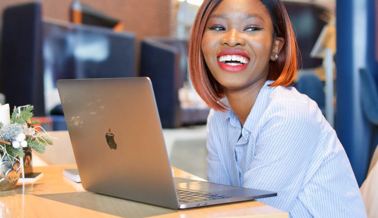 Young lady with laptop on her able, smiling