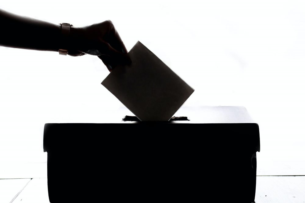 A hand casting a ballot in an election