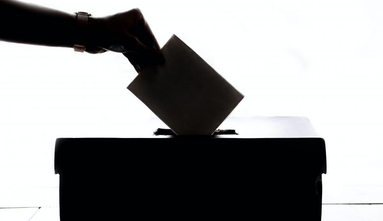 A hand casting a ballot in an election