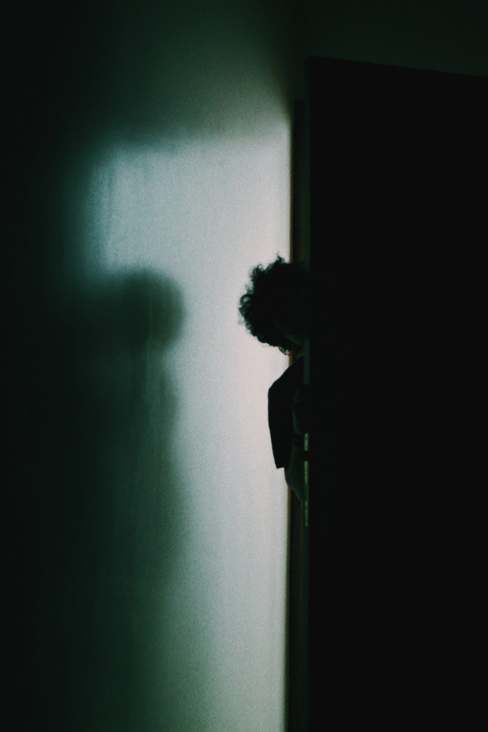 Someone hiding behind a door in a dark room
