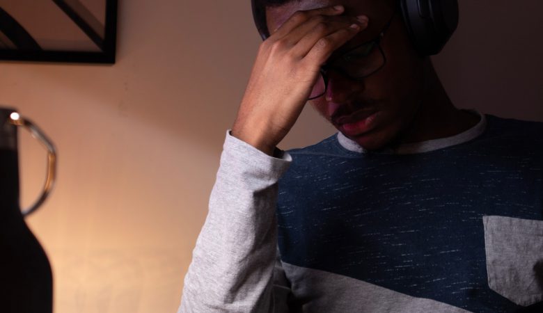 A young man resting his hand on his forehead, lookng tired and frustrated